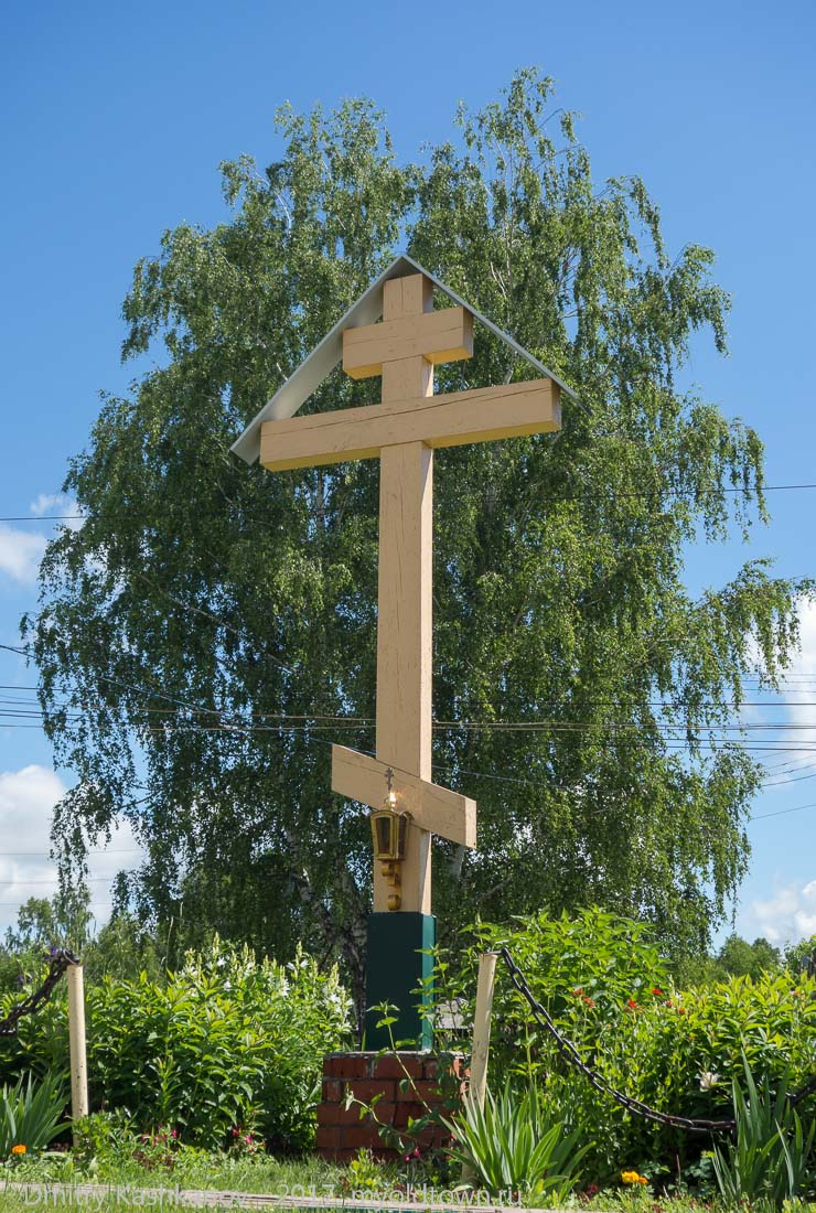 Деревянный крест на фоне кроны березы
