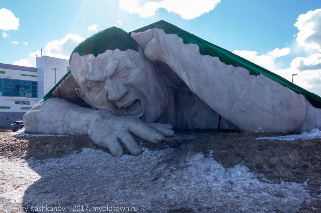 Скульптура. Огромный человек лезет из-под земли. Фото